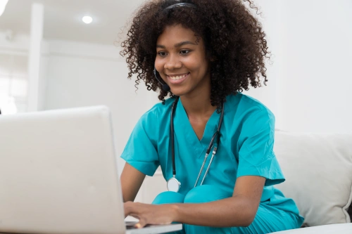 Medical assistant studying for medical assisting certification program on laptop